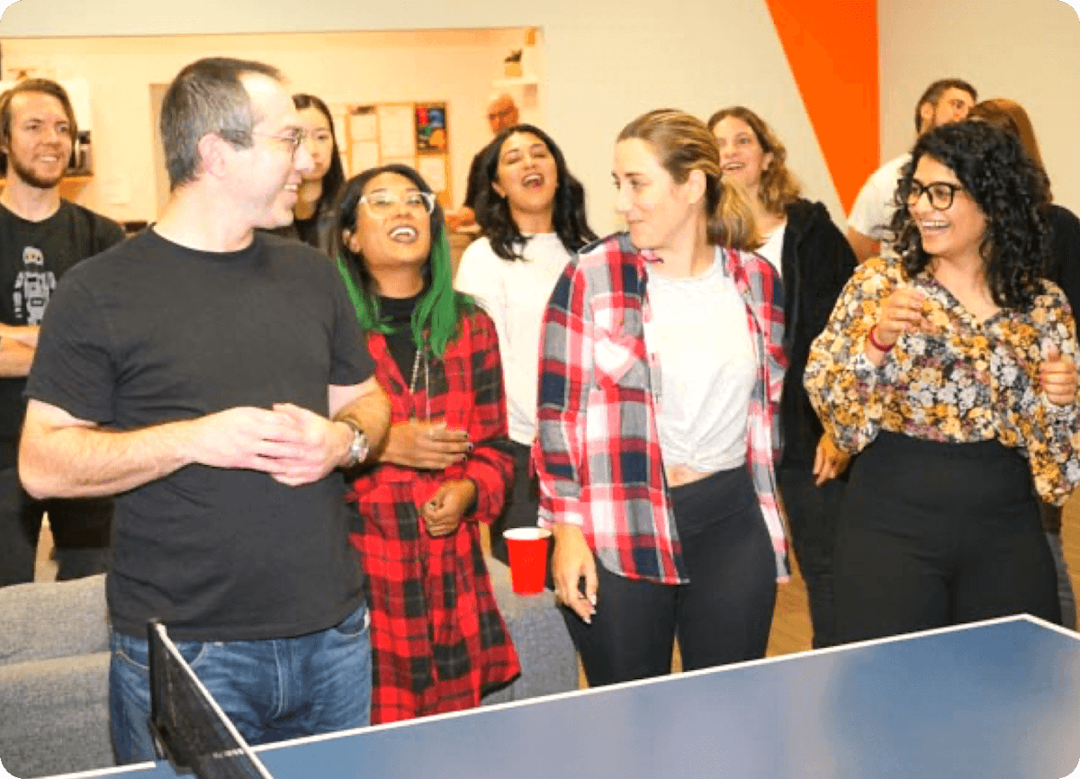 A group of people playing ping pong in an office.