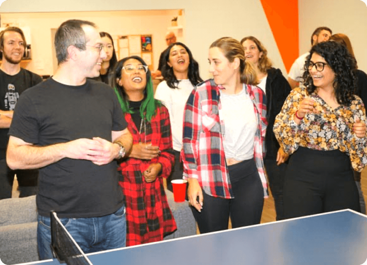 A group of people playing ping pong in an office.