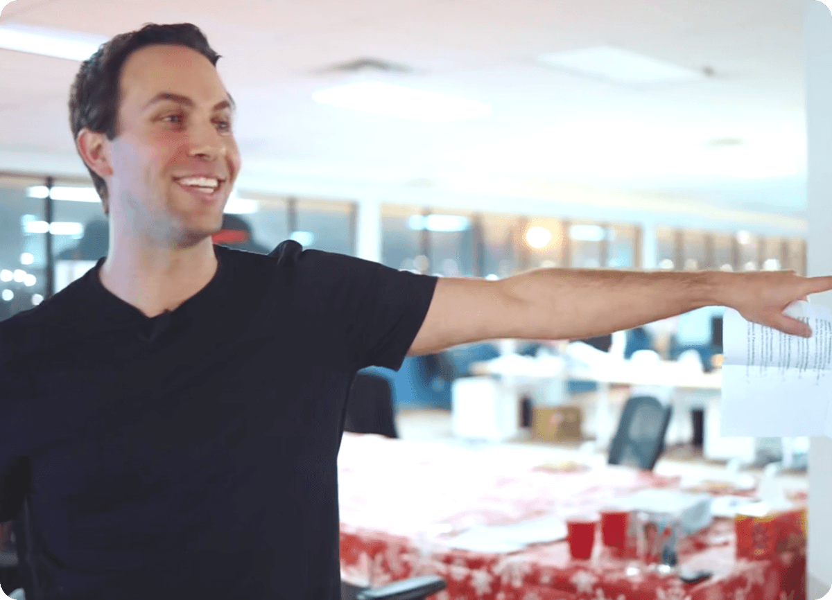 A man pointing to a white board in an office.