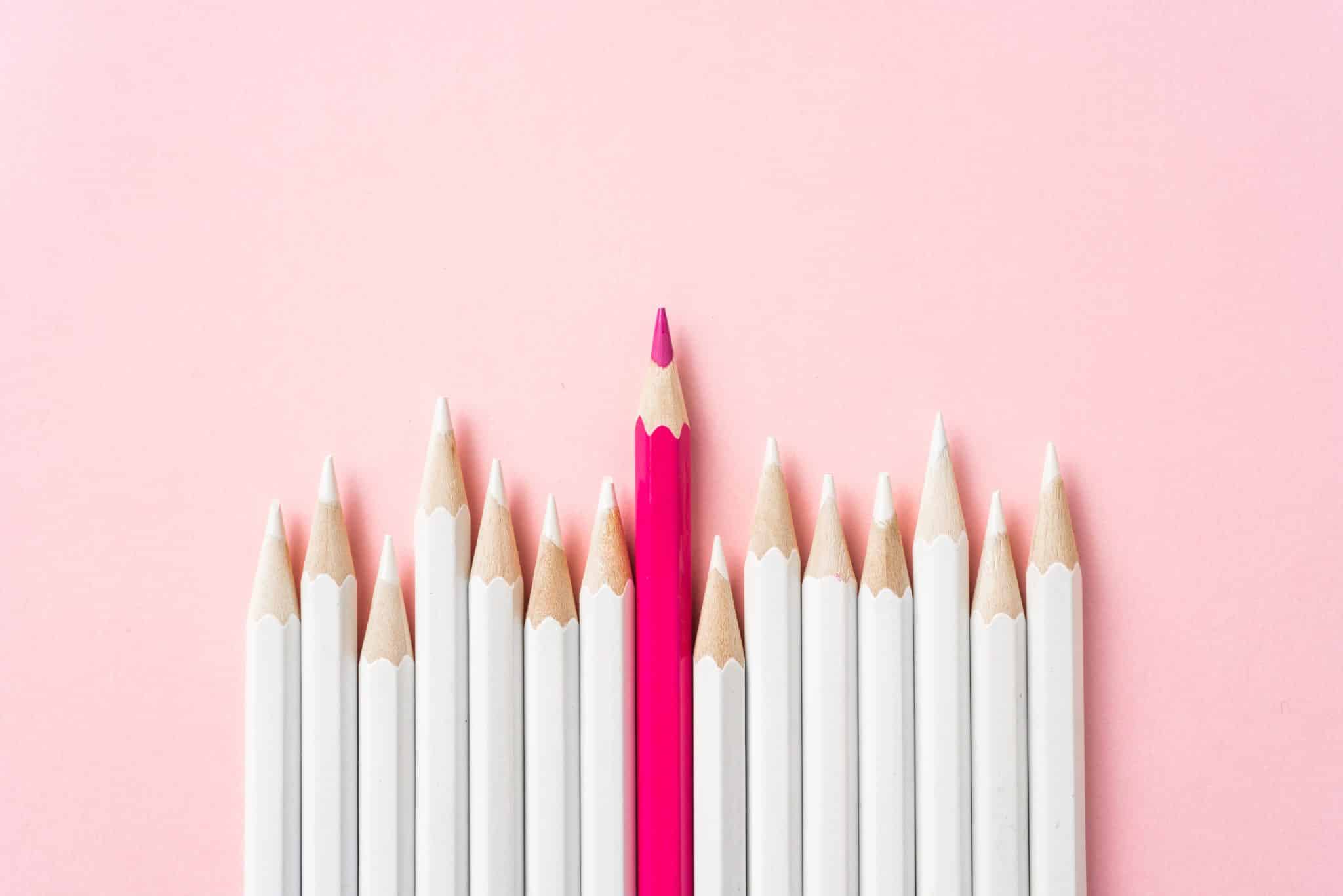 One pink pencil amongst many white pencils