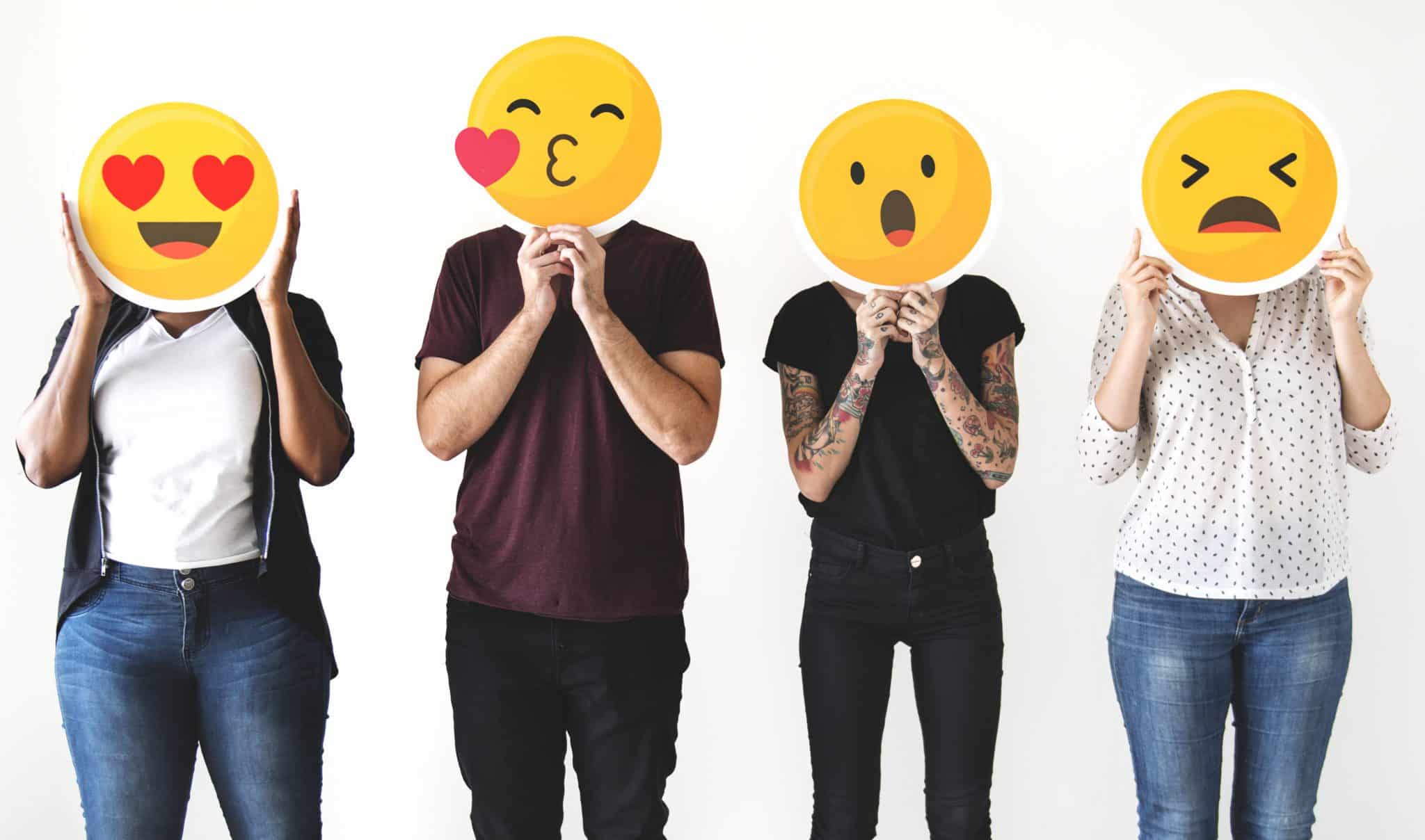 Four people holding emojis