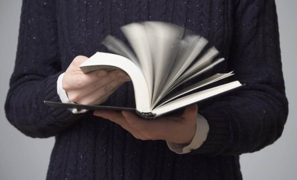 Woman's hands flipping a black book