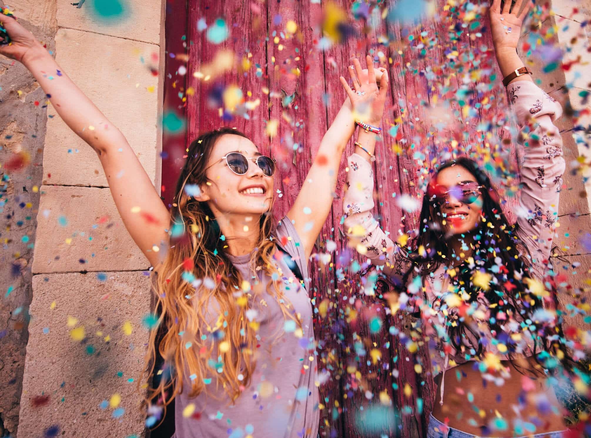 Two women are throwing confetti at each other.