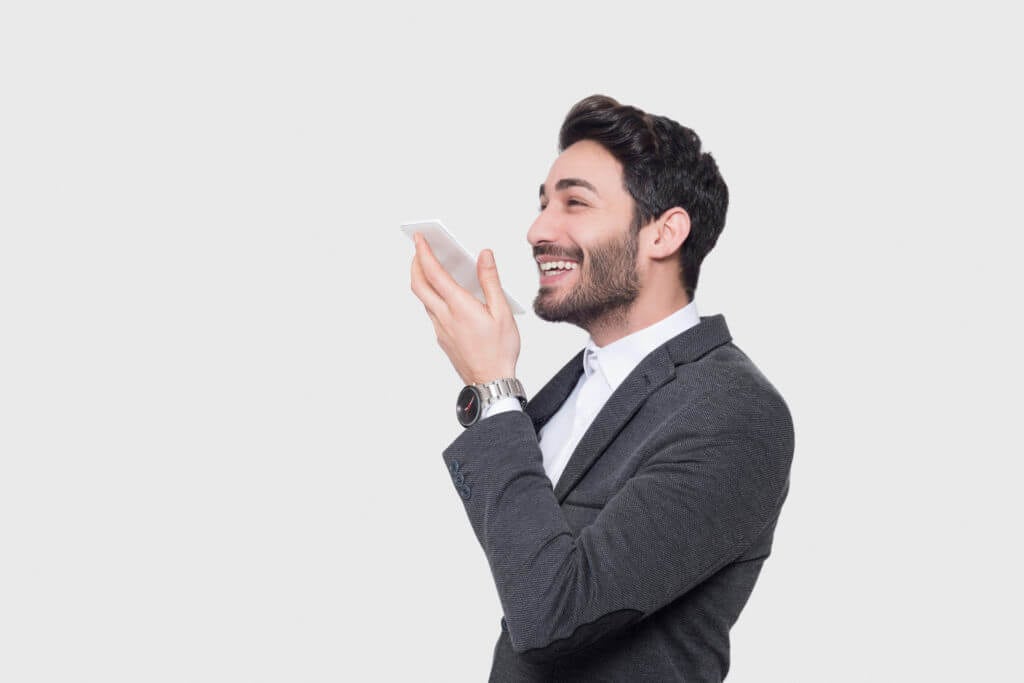 A man in a suit is holding his phone up to his face.