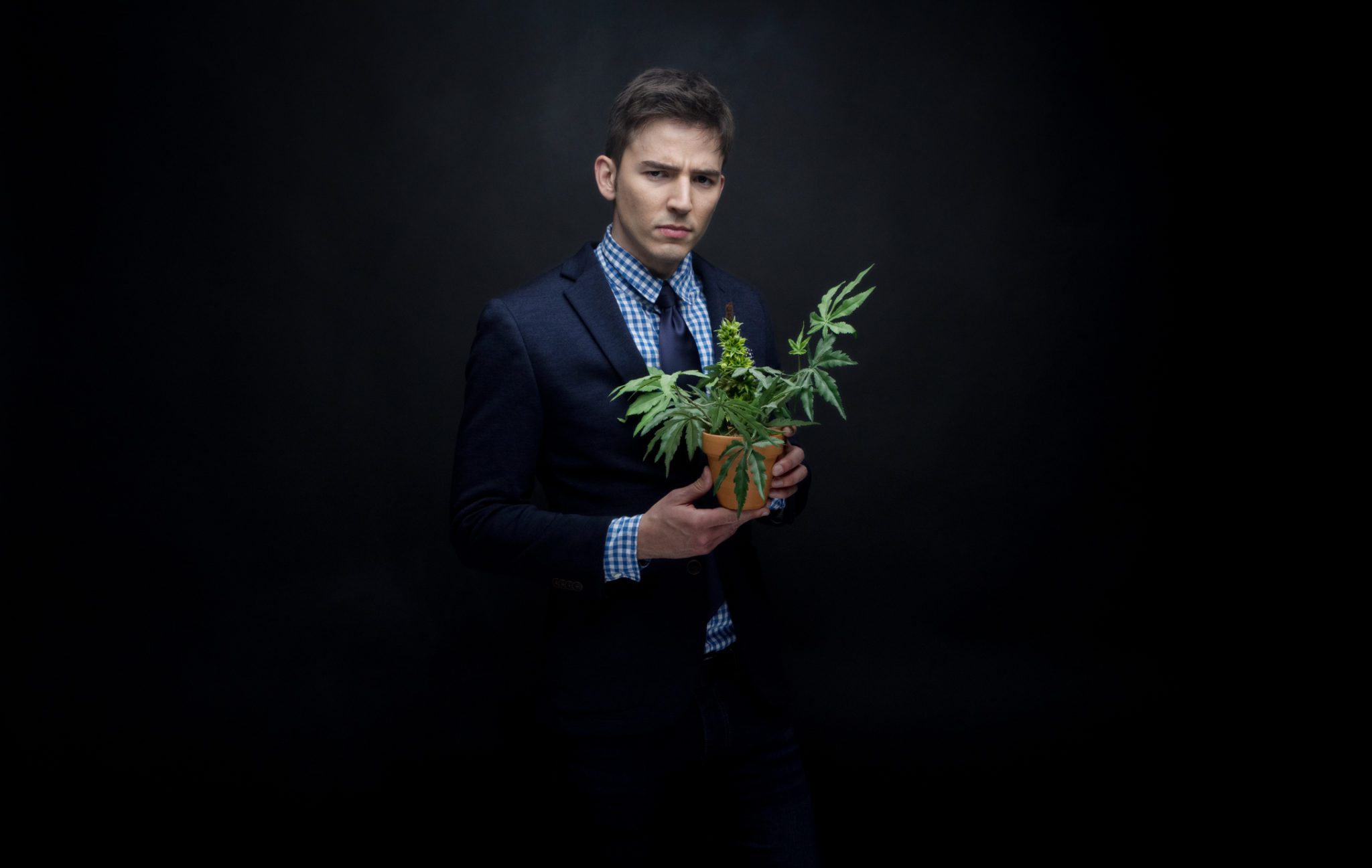 A man in a suit showcasing cannabis marketing with a pot of marijuana.