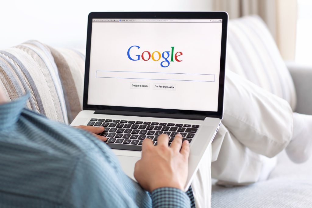 Man typing on Google on laptop