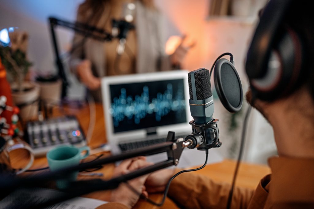 Selective focus of microphone used by young man and woman while recording podcast during an interview and doing a live broadcast in a studio