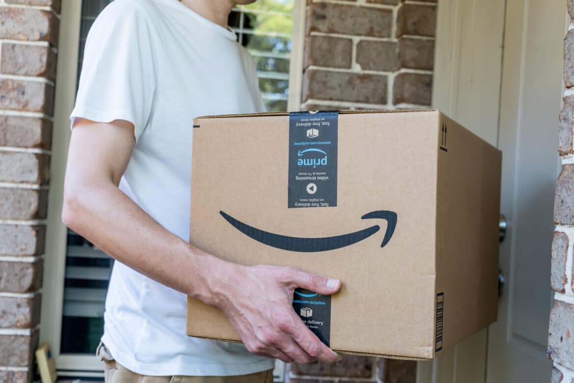 Man holding box from Amazon entering his home.