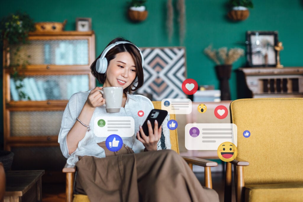 Gen Z woman sitting on her phone with various digital media icons floating around her.