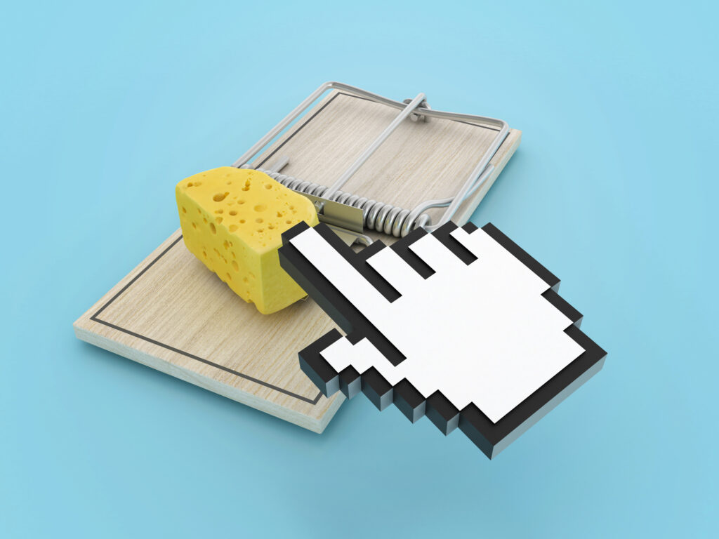 Mouse hand clicking on a piece of cheese in a mouse trap. 