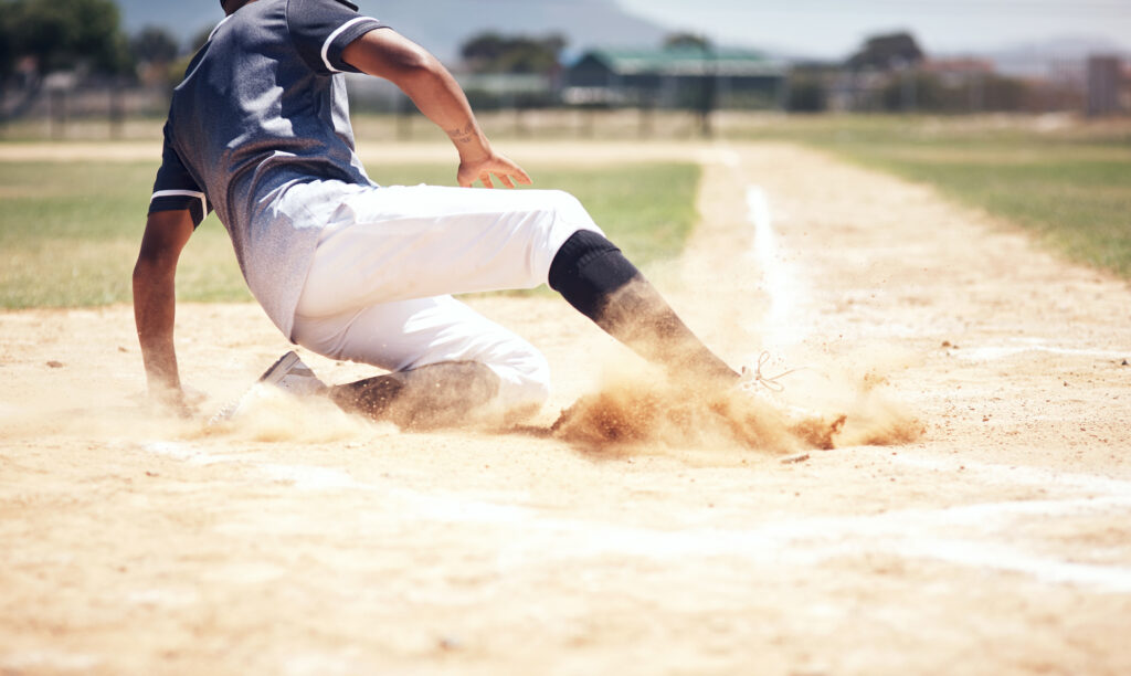 Baseball player sliding into home plate for a point. 