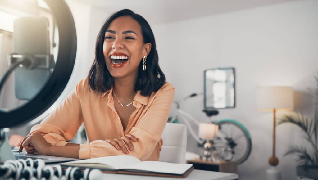 Social media content creator utilizing influencer marketing to stream a live tutorial, laughing and talking to her online followers. 