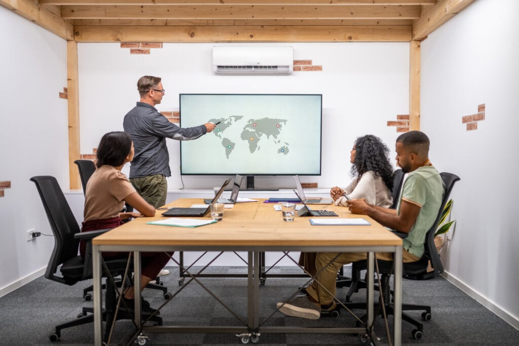 Marketing strategist pointing at a global content map on a digital screen during a copywriting strategy session.